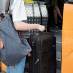 Młoda kobieta wchodzi do busu z plecakiem i walizką